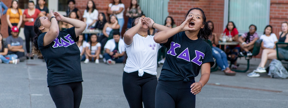 three greek life student leaders cheering during recruitment